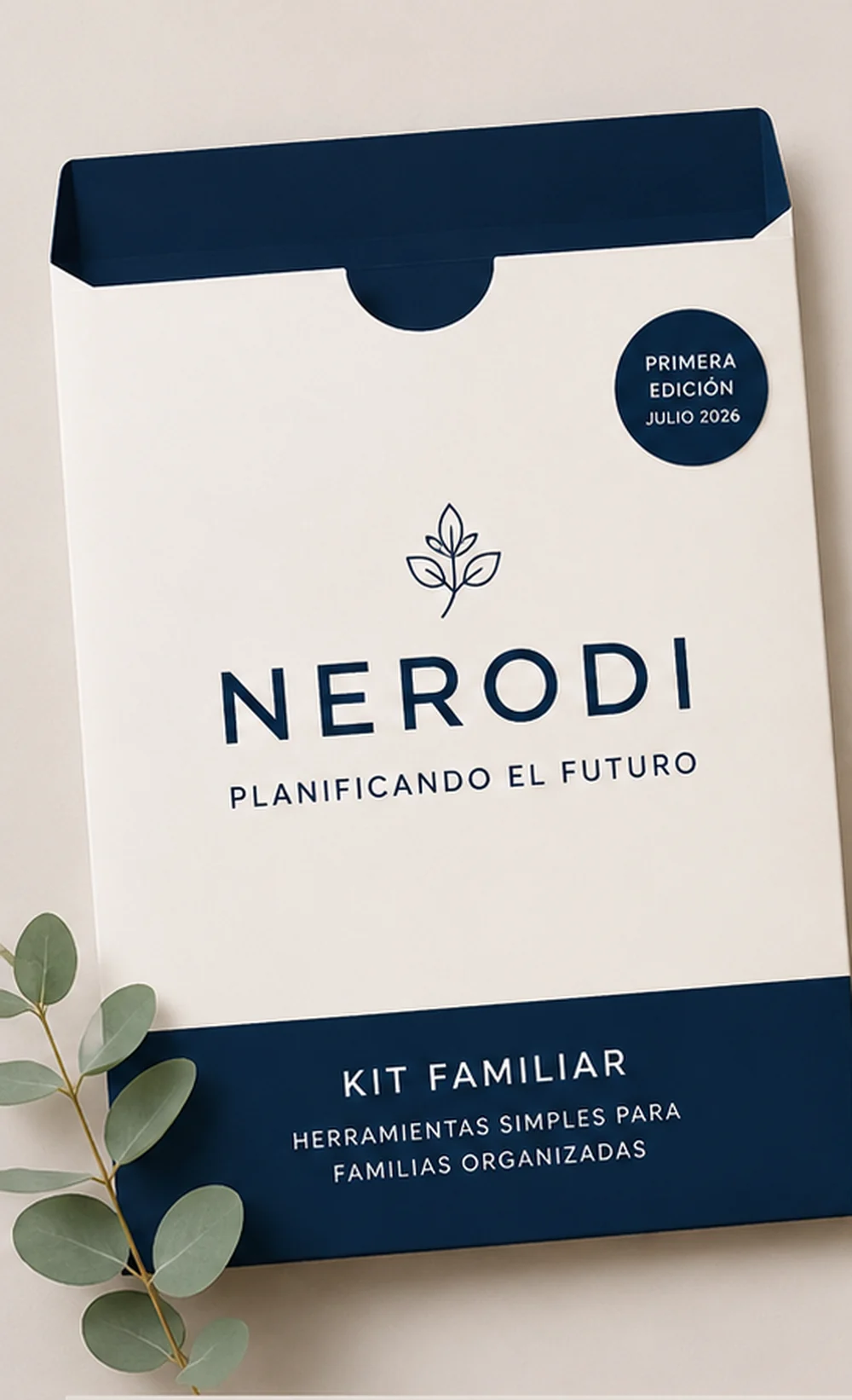 The Nerodi Family Kit: a bone-coloured folder with a deep navy band, first edition July 2026, beside a sprig of eucalyptus.